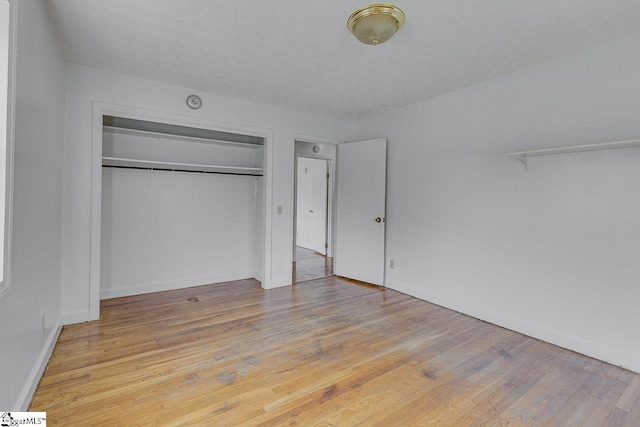 unfurnished bedroom with light wood-style flooring, baseboards, and a closet