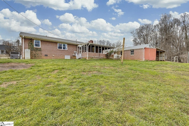 back of property with an outbuilding, crawl space, brick siding, and a lawn