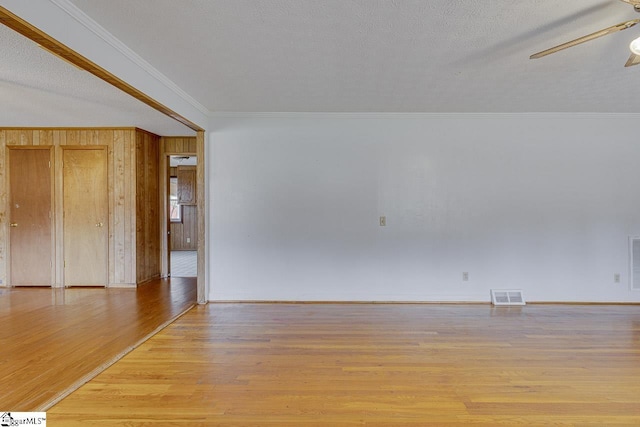 spare room featuring visible vents, light wood-style flooring, ceiling fan, a textured ceiling, and crown molding