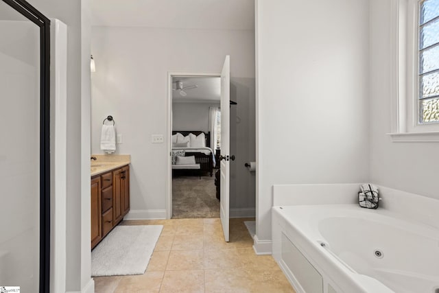 ensuite bathroom with connected bathroom, vanity, tile patterned flooring, a jetted tub, and baseboards