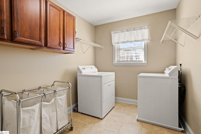 washroom featuring light tile patterned flooring, washing machine and dryer, cabinet space, and baseboards