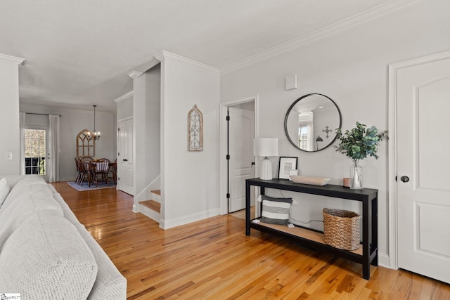 entrance foyer with baseboards, ornamental molding, stairs, light wood-type flooring, and a notable chandelier