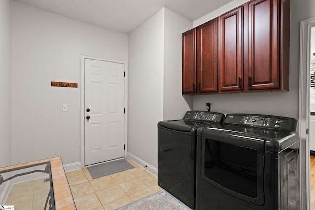 clothes washing area featuring cabinet space, light tile patterned floors, baseboards, and washer and dryer