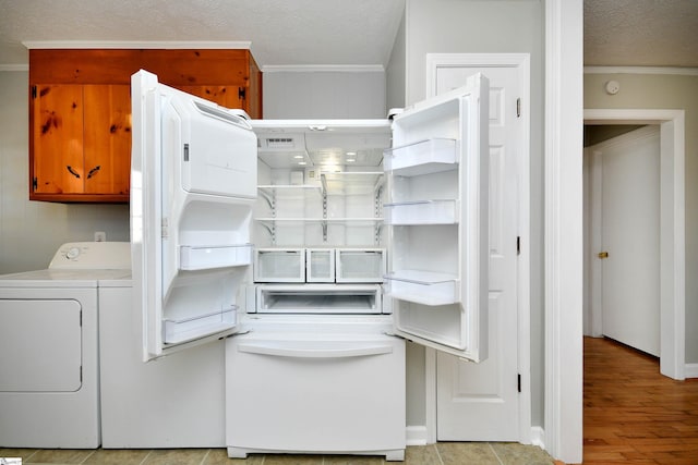 interior space featuring ornamental molding, washing machine and dryer, cabinet space, and a textured ceiling