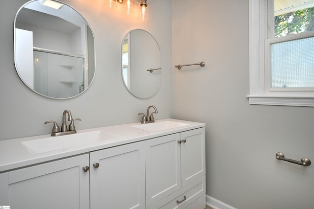 bathroom with an enclosed shower, a sink, baseboards, and double vanity