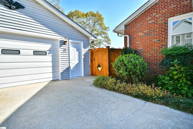 view of side of property with an attached garage, a gate, and brick siding