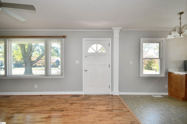 foyer entrance with ornamental molding, light wood-type flooring, visible vents, and baseboards