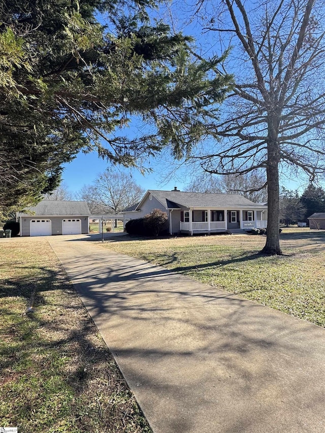 view of front facade featuring covered porch, an outdoor structure, a garage, and a front yard