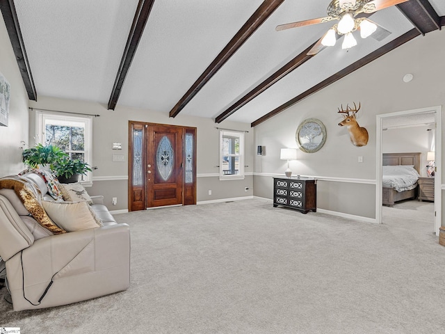 carpeted living room featuring vaulted ceiling with beams, ceiling fan, baseboards, and a textured ceiling