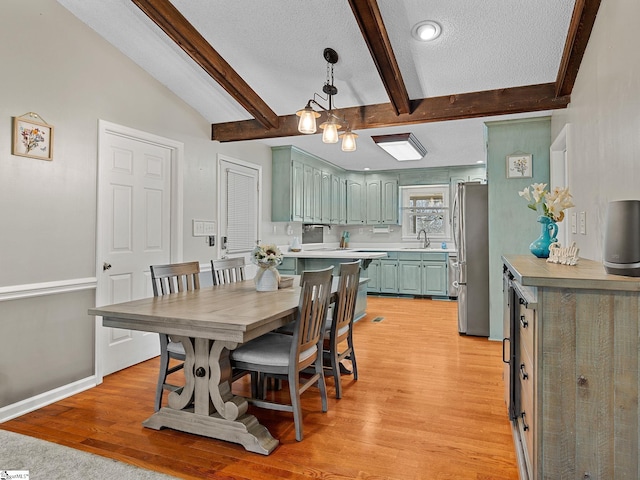 dining area with light wood-style floors, lofted ceiling with beams, a textured ceiling, and baseboards