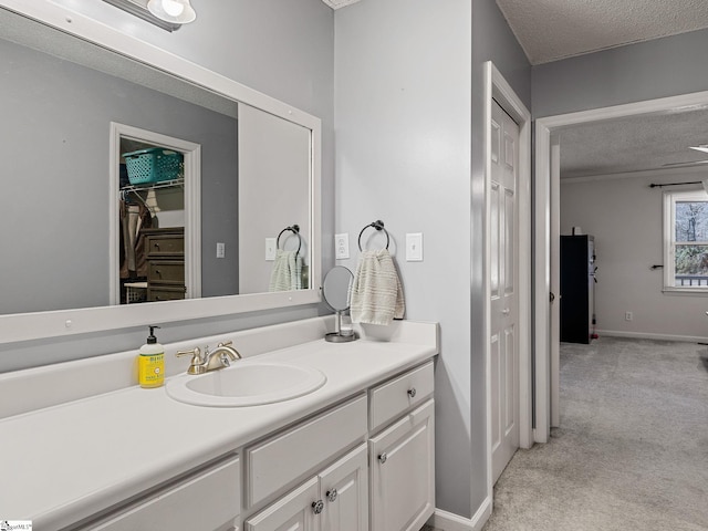 bathroom featuring baseboards, a textured ceiling, and vanity