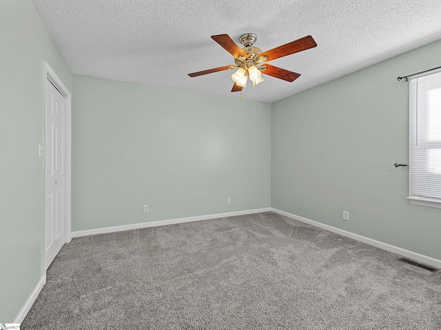 carpeted spare room featuring visible vents, ceiling fan, a textured ceiling, and baseboards