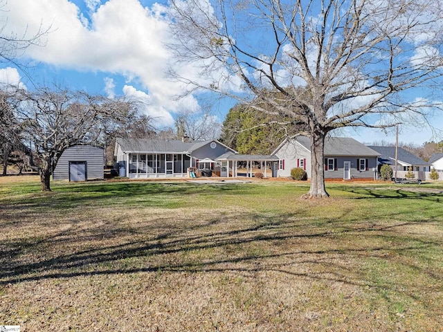 back of property featuring a sunroom, a yard, and an outbuilding