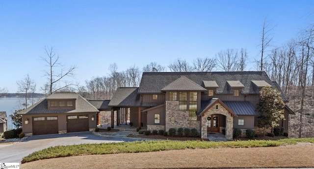 craftsman inspired home featuring an attached garage, board and batten siding, a standing seam roof, stone siding, and driveway