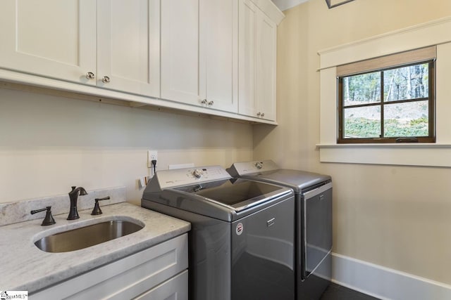 clothes washing area with independent washer and dryer, a sink, and cabinet space