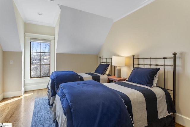 bedroom featuring lofted ceiling, baseboards, and wood finished floors