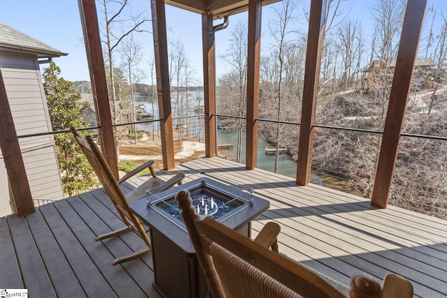 wooden terrace with an outdoor fire pit and a water view