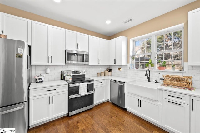 kitchen featuring appliances with stainless steel finishes, white cabinets, dark wood finished floors, and light countertops