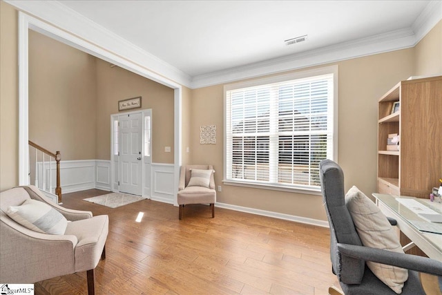 home office with a wainscoted wall, visible vents, a decorative wall, ornamental molding, and wood finished floors