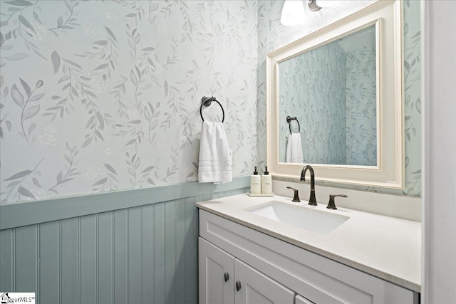 bathroom with wainscoting, vanity, and wallpapered walls