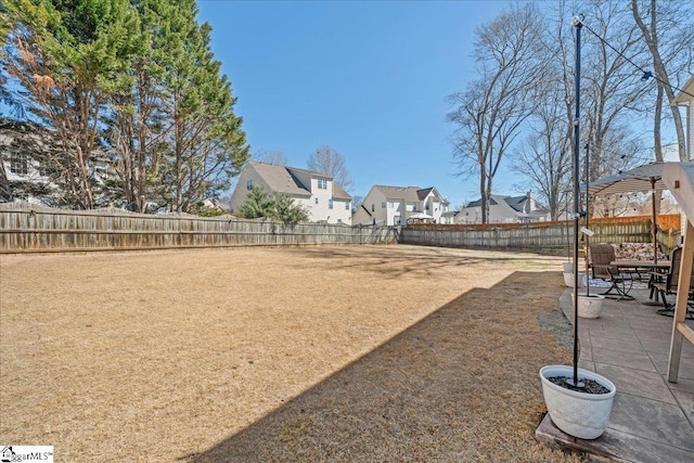 view of yard with a fenced backyard, a residential view, and a patio