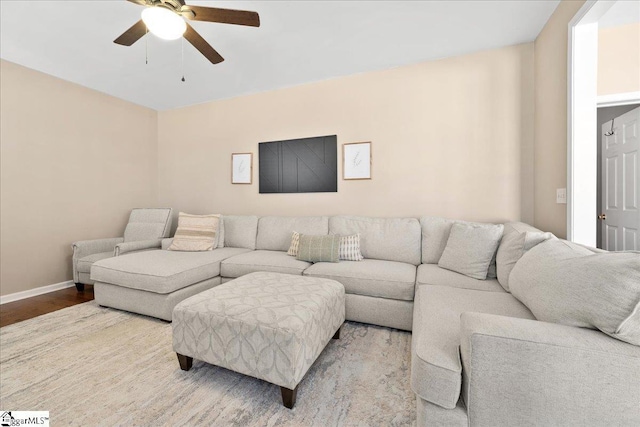 living room featuring ceiling fan, baseboards, and wood finished floors