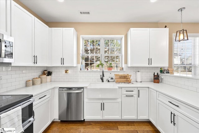 kitchen featuring white cabinets, visible vents, stainless steel appliances, and a sink