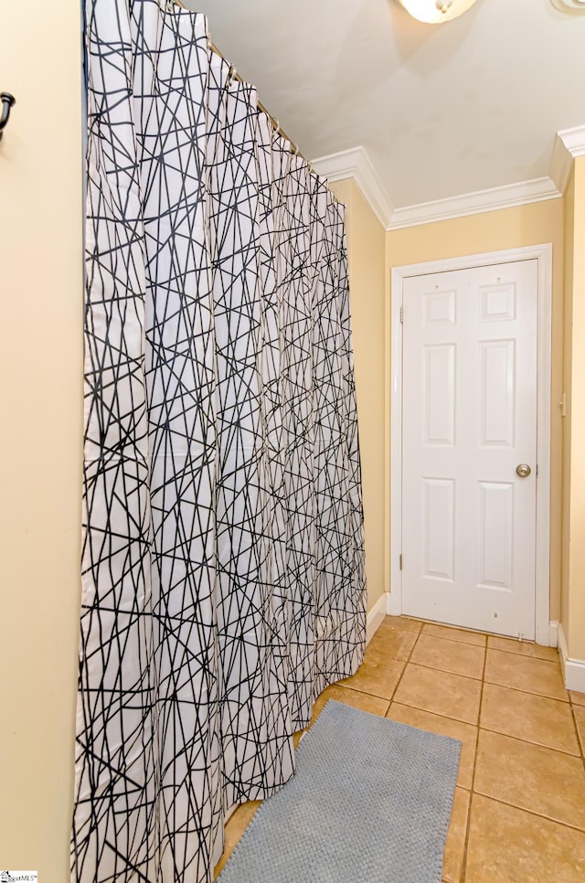 interior space with ornamental molding, a shower with shower curtain, baseboards, and tile patterned floors