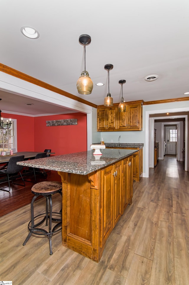 kitchen featuring ornamental molding, brown cabinetry, visible vents, and light wood-style floors