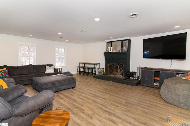 living area with recessed lighting, visible vents, wood finished floors, and ornamental molding