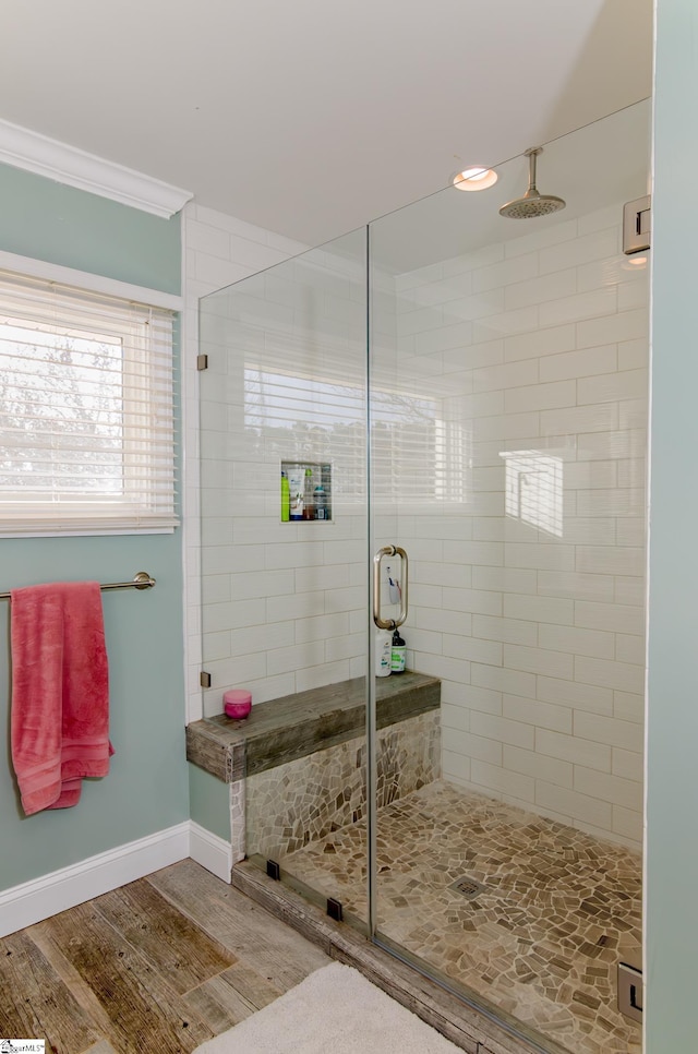 full bath with baseboards, a stall shower, wood finished floors, and crown molding