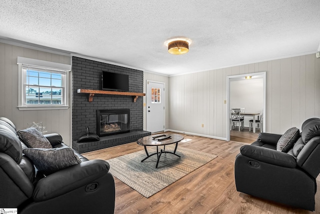 living area featuring a brick fireplace, a textured ceiling, and wood finished floors