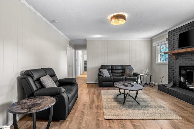 living room featuring ornamental molding, a fireplace, a textured ceiling, and wood finished floors