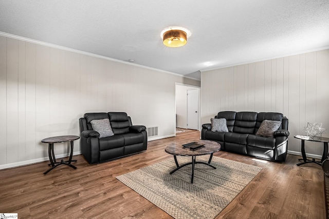 living area with crown molding, visible vents, a textured ceiling, wood finished floors, and baseboards