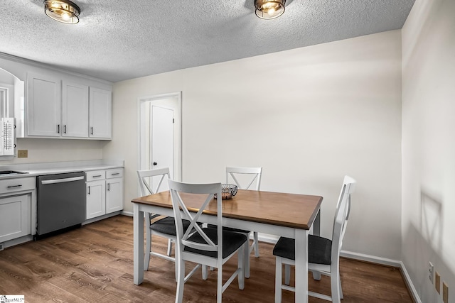 dining space with a textured ceiling, dark wood finished floors, and baseboards