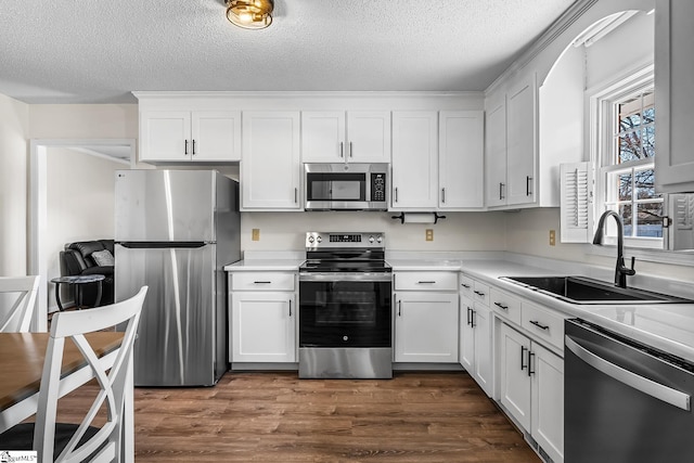 kitchen featuring stainless steel appliances, dark wood finished floors, white cabinetry, and a sink