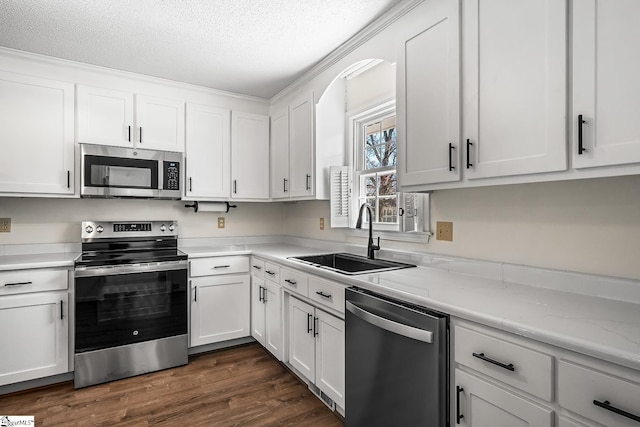 kitchen with dark wood-style floors, stainless steel appliances, a sink, and white cabinetry