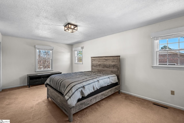 carpeted bedroom featuring visible vents, a textured ceiling, and baseboards