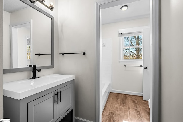 bathroom featuring baseboards, wood finished floors, and vanity