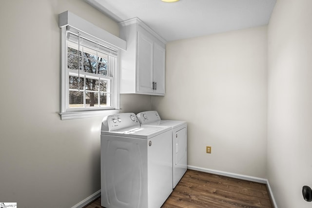 laundry room featuring dark wood-type flooring, washing machine and dryer, cabinet space, and baseboards