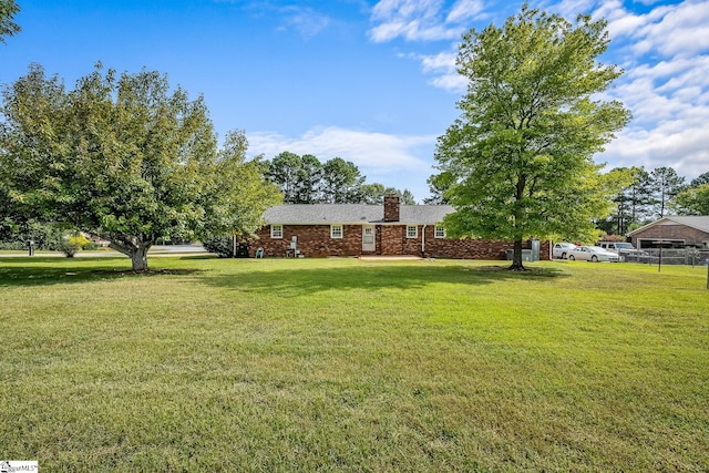 view of front of property featuring a chimney, a front lawn, and brick siding