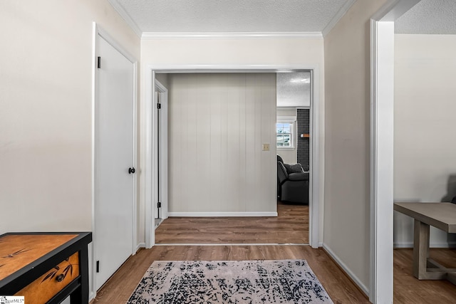 hall with ornamental molding, a textured ceiling, and wood finished floors