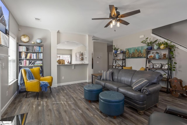 living area with arched walkways, visible vents, ceiling fan, wood finished floors, and baseboards