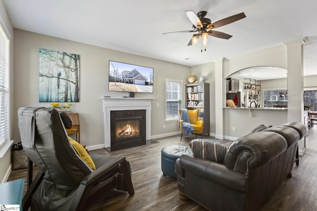 living room featuring ceiling fan, wood finished floors, a fireplace with flush hearth, and baseboards