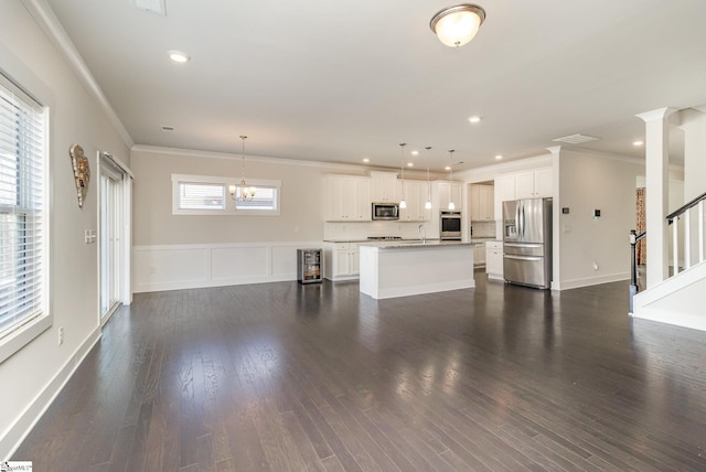 unfurnished living room featuring ornamental molding, stairway, a sink, and dark wood finished floors