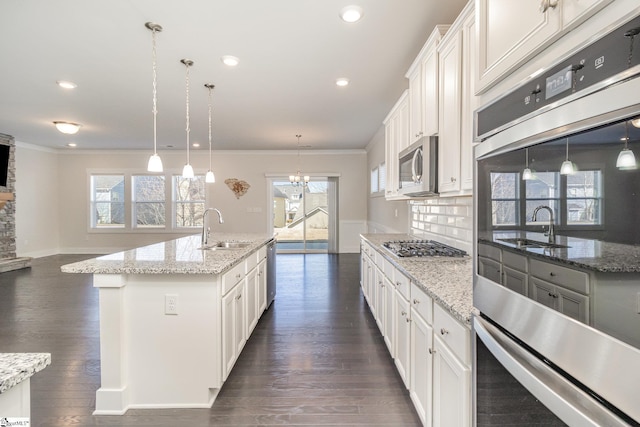 kitchen with dark wood-style floors, ornamental molding, a sink, stainless steel appliances, and backsplash