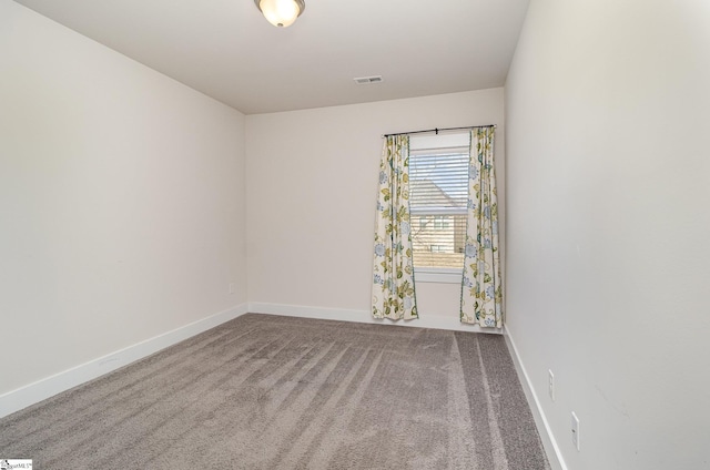 spare room featuring carpet flooring, visible vents, and baseboards