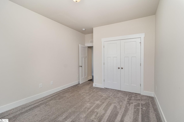 unfurnished bedroom with carpet, visible vents, baseboards, and a closet