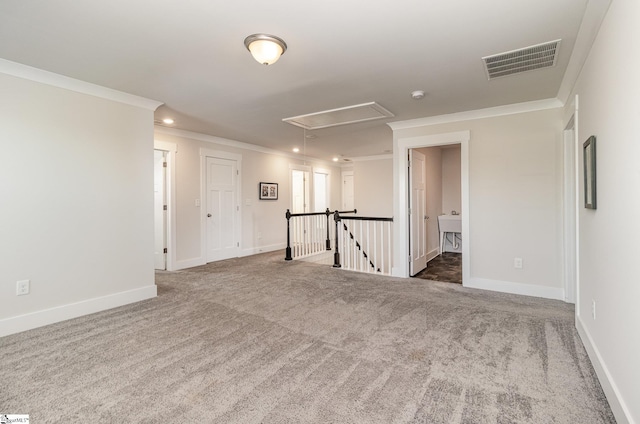 carpeted spare room featuring attic access, visible vents, baseboards, and ornamental molding