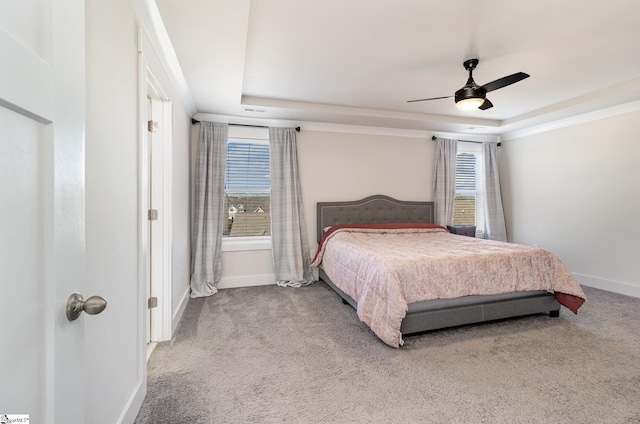 bedroom with carpet flooring, a raised ceiling, and baseboards